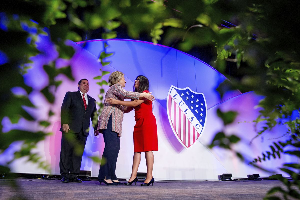 In this July 14, 2016 photo Democratic presidential candidate Hillary Clinton, accompanied by then-LULAC President Roger C. Rocha, Jr., left, hugs University of Texas student Dreamer Lizeth Urdiales, right, as she arrives to speaks at the 87th League of United Latin American Citizens National Convention at the Washington Hilton in Washington. LULAC, the nation