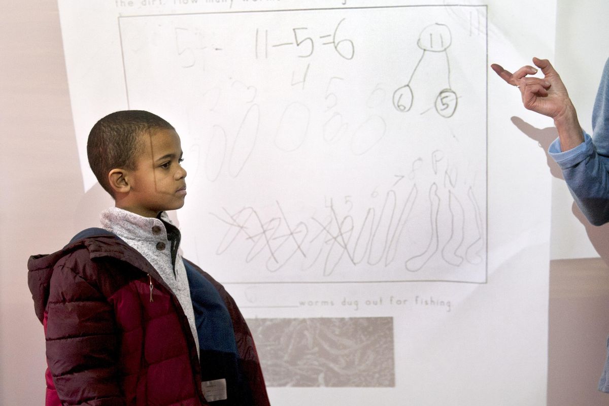Courtney Vaughn stands in front of his worksheet as teacher Marion Bageant talks about his work in her first grade class at Garfield Elementary on Wednesday, Jan. 16, 2019. She is using visual thinking strategies, or VTS, a teaching method for younger students that relies on reflect-and-response techniques. (Kathy Plonka / The Spokesman-Review)