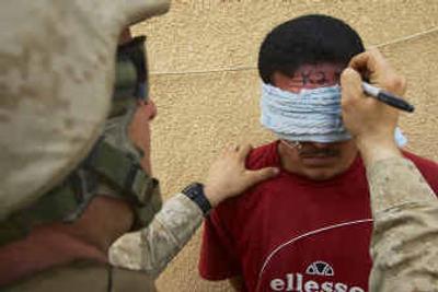 
A U.S. Marine writes an identification number on the forehead of an Iraqi man detained during a search in Haditha on Wednesday during a sweep of the troubled city. 
 (Associated Press / The Spokesman-Review)