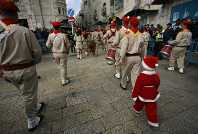 A Palestinian Christian boy follows a band as they play and march through Manger Square next to the Church of the Nativity in  Bethlehem on Wednesday.  (Associated Press / The Spokesman-Review)