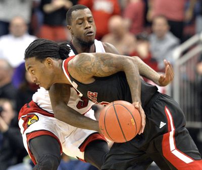 North Carolina State's Anthony Barber, front, tries to drive around Louisville's Chris Jones. (Associated Press)