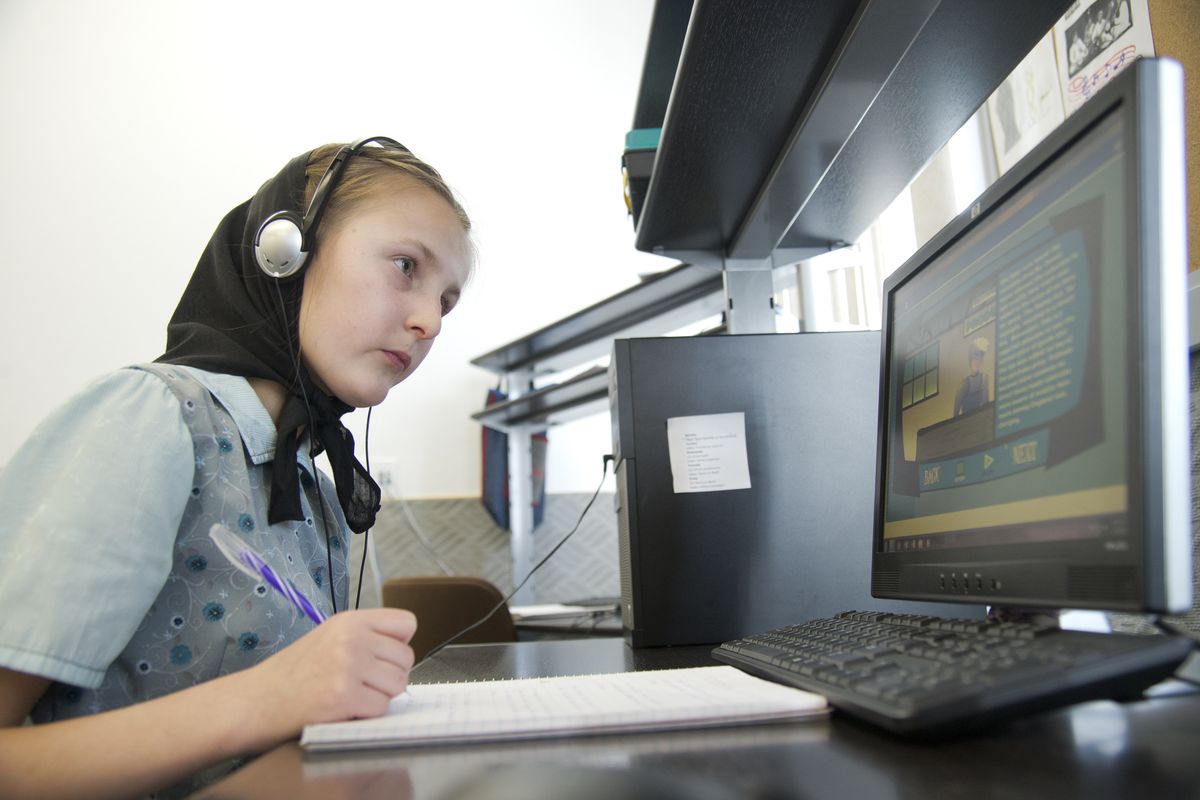 Sydney Stahl, a seventh-grader in the Hutterite community in rural Ritzville, works on school lessons on a computer in the Hutterite colony’s private school Wednesday. The older students use a state-approved online curriculum along with lectures and assignments from an in-school teacher. (PHOTOS BY JESSE TINSLEY)