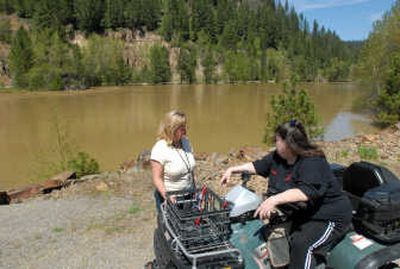 
Sandy Von Behren, left, of the Kootenai County Office of Emergency Management, talks with Lee Ann Basinger, of Cataldo, on Saturday on the banks of the Coeur d'Alene River, which is running very high and not expected to peak before Monday. Water has inundated low-lying fields and roads. 
 (Jesse Tinsley / The Spokesman-Review)