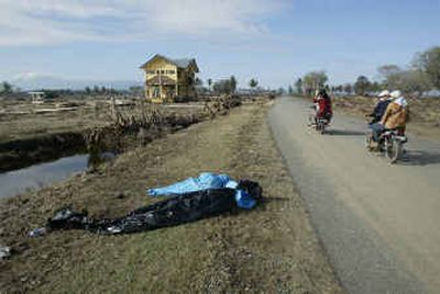 
Bodies lie in bags on the roadside to be picked up by rescuers in the outskirts of Banda Aceh, Indonesia, on Friday. 
 (Associated Press photos / The Spokesman-Review)