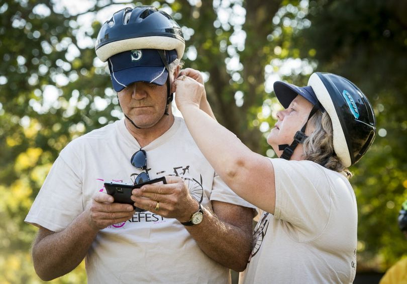 Jane Scott adjusts her husband David's bike helmet before doing a nine-mile SpokeFest ride on Sunday, Sept. 13, 2015, in downtown Spokane, Wash. (Colin Mulvany / The Spokesman-Review)