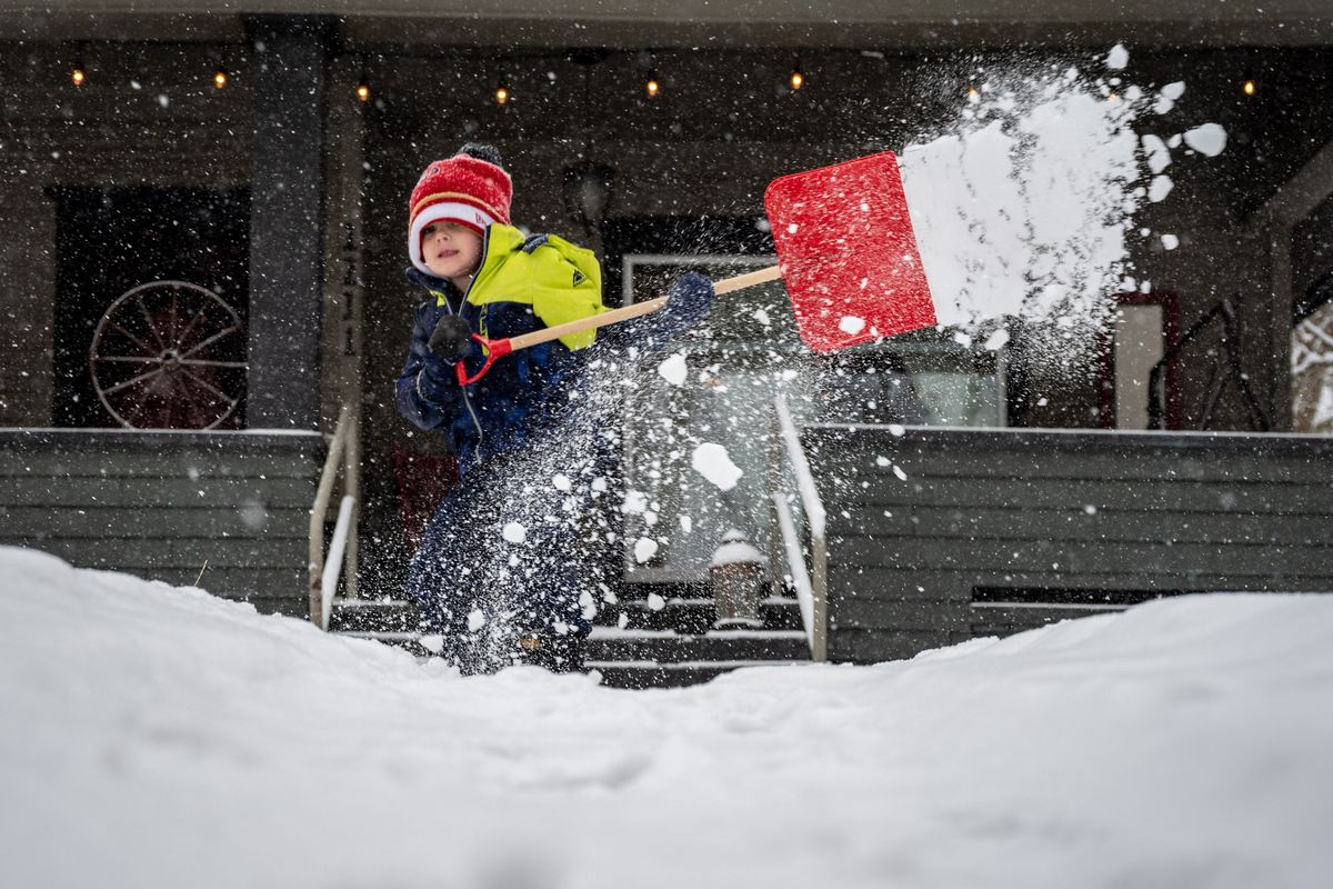Ari Apfelbaum, 4, helps clear the front walkway of snow at his family’s home on West 17th Avenue on Monday while his dad, Jordan, shoveled the sidewalk.  (COLIN MULVANY/THE SPOKESMAN-REVIEW)