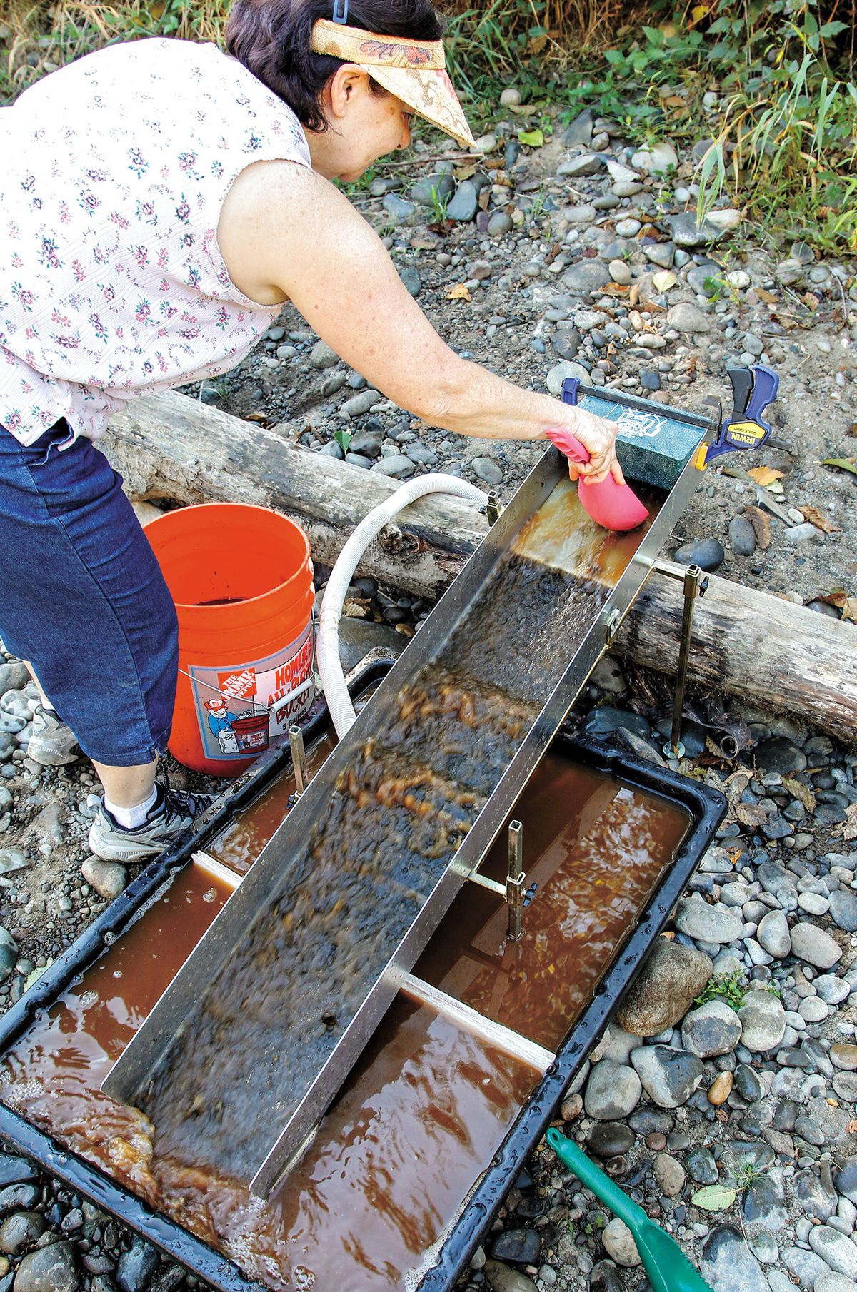 Rebecca Fuller of Troutdale pours spoonfuls of dirt into the stream of water. (Associated Press)
