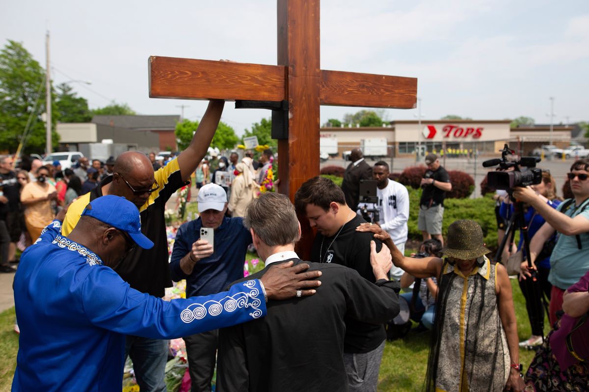 A group prays at the site of a memorial for the victims of the Buffalo supermarket shooting outside the Tops Friendly Market on Saturday, May 21, 2022, in Buffalo, N.Y. Tops was encouraging people to join its stores in a moment of silence to honor the shooting victims Saturday at 2:30 p.m., the approximate time of the attack a week earlier. Buffalo Mayor Byron Brown also called for 123 seconds of silence from 2:28 p.m. to 2:31 p.m., followed by the ringing of church bells 13 times throughout the city to honor the 10 people killed and three wounded.  (Joshua Bessex)