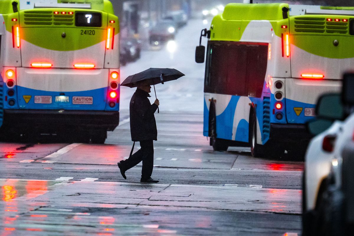 A pedestrian walks across a rain-soaked Riverside Avenue on Monday in downtown Spokane.  (COLIN MULVANY /THE SPOKESMAN-REV)