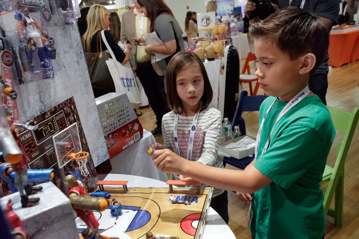 Evan and Jillian of EvanTubeHD try NBA Heroes, by Jazwares, at the TTPM Holiday Showcase in New York in October. (Associated Press)