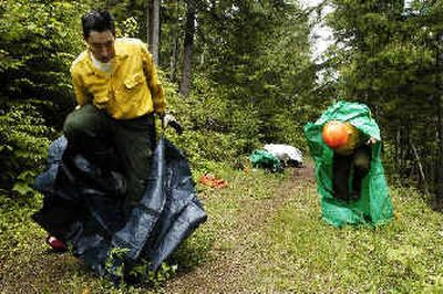 
Tyrone Daniels, left, an advanced wildland firefighter, struggles into a personal fire shelter during practice on a muddy road near Camp Mivoden on Hayden Lake on Tuesday afternoon. Advanced firefighters will vie for crew and squad boss jobs when the fire season starts and must have the class Daniels was taking to qualify. Beginning and advanced wildland firefighters are training this week to be ready for call-up on local and distant fires.
 (Jesse Tinsley / The Spokesman-Review)