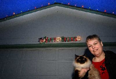 
Vicky Gould with her cat Annie shows off the Christmas lights her daughter and son-in-law, Genna and Fred Seidel, bought and put up on her home on Sharpsburg Avenue. Gould wrote a letter to Santa to reward them for their Christmas surprise.
 (Liz Kishimoto / The Spokesman-Review)