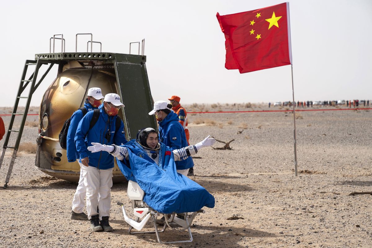 In this photo released by China's Xinhua News Agency, Chinese astronaut Ye Guangfu sits outside return capsule of the Shenzhou-13 manned space mission after landing at the Dongfeng landing site in northern China's Inner Mongolia Autonomous Region, Saturday, April 16, 2022. Three Chinese astronauts returned to Earth on Saturday after six months aboard China's newest space station in the longest crewed mission to date for its ambitious space program.  (Cai Yang)