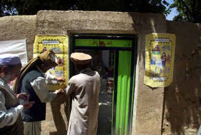 
Afghan election officials put up election participation posters outside a mosque in Baba Qushquar village. 
 (Associated Press / The Spokesman-Review)