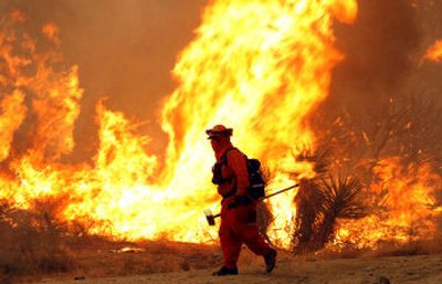
A firefighter walks in front of a wildfire near Morongo Valley, Calif., which is about 120 miles east of Los Angeles, on Thursday. 
 (AP / The Spokesman-Review)
