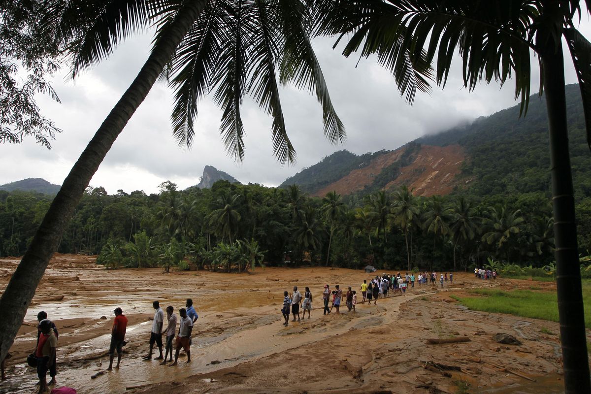 Sri Lankan landslide survivors walk through the mud after a landslide in Elangipitiya village in Aranayaka about 72 kilometers (45 miles) north east of Colombo, Sri Lanka, Wednesday, May 18, 2016. (Eranga Jayawardena / AP)