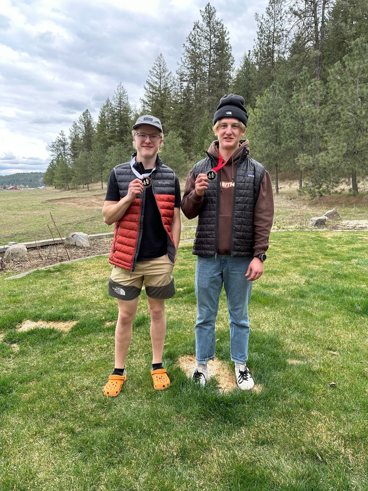 Alex Hermanson (left) and his twin brother, Matt Hermanson (right), display their medals earned at last year’s Hub-A-Palooza mountain bike festival at Beacon Hill, while standing in their backyard track the two built while in high school. (GoFundMe)
