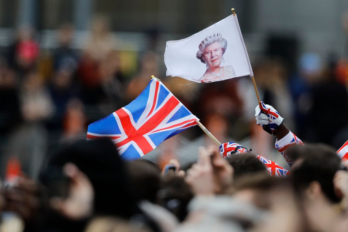 FILE - A man waves a British union flag and a flag bearing the image of Britain