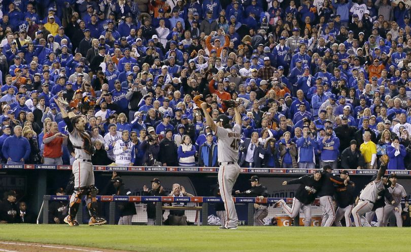 A sea of blue-clad Kansas City Royals fans can only watch as Giants catcher Buster Posey and pitcher Madison Bumgarner celebrate after the final out of Game 7. (Associated Press)
