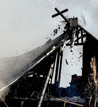 A cross made of steel breaks loose as crews continued to battle the arson blaze at St. Ann's Catholic Church in Bonners Ferry on Thursday, April 21, 2016. (Kathy Plonka / The Spokesman-Review)