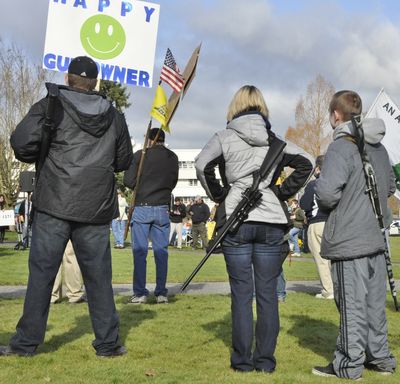 The Morris family – father Matt, mother Carey and son Josh – brought rifles, shotguns, pistols and a sign from their home in Aberdeen, Wash., to the gun rights rally Friday in Olympia. (Jim Camden)