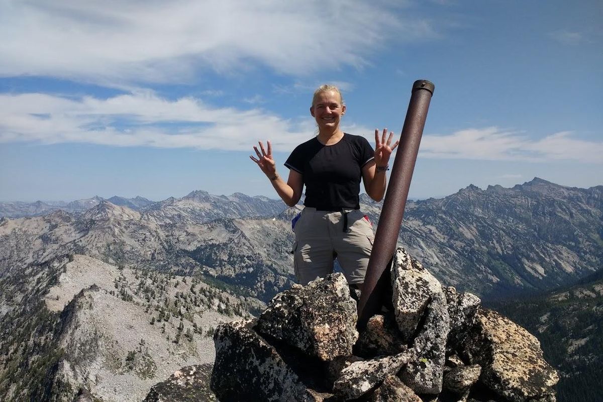 Terri Rowe, of Meridian, stands on top of Bare Peak NW in Idaho County on Aug. 6, 2019, while holding up four fingers on each hand to symbolize Idaho’s 44 counties. Rowe became the first woman and only the eighth person to ever reach the highpoint of each of Idaho’s counties when she summited Bare Peak. (TERRI ROWE / COURTESY)