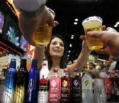 
Anheuser Busch's new aluminum bottles and Peels, their new natural fruit flavored malt liquors, are on display as bartender Tiffany Kamykowski serves two beers at the Food Marketing Institute show in Chicago on Sunday. 
 (Associated Press / The Spokesman-Review)