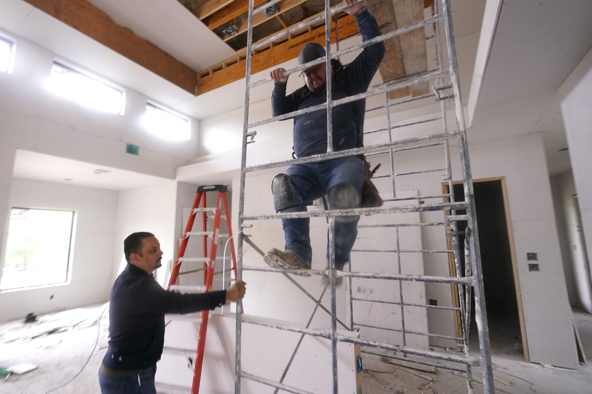 Joshua Correa, left, steadies a scaffolding for Samuel as they work at a home under construction in Plano, Texas, Tuesday, May 3, 2022. There are an estimated 2 million fewer immigrants than expected in the United States, helping fuel a desperate scramble for workers in many sectors, from meatpacking to homebuilding, that are also contributing to shortages and price increases. Correa has struggled to hire supervisors for his work sites, with immigrant job candidates demanding $100,000 yearly pay.  (LM Otero)