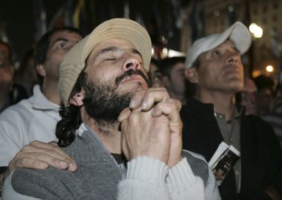 Government supporters pray as they watch a large screen outside the Parliament in Buenos Aires on Thursday.  (Associated Press / The Spokesman-Review)