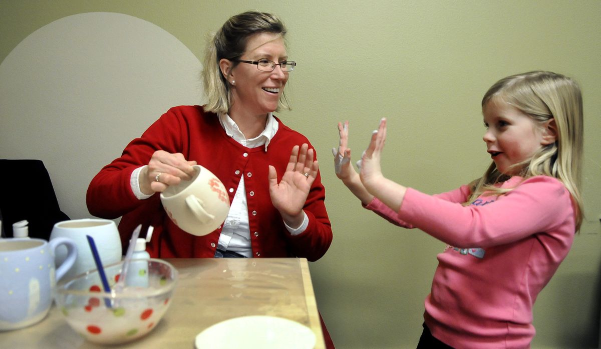 Megan Tallman, 6, shows off paint-covered hands to her mother, Dawn Tallman, after she imprinted her palms on a mug at Polka Dot Pottery on Saturday.  (Dan Pelle)