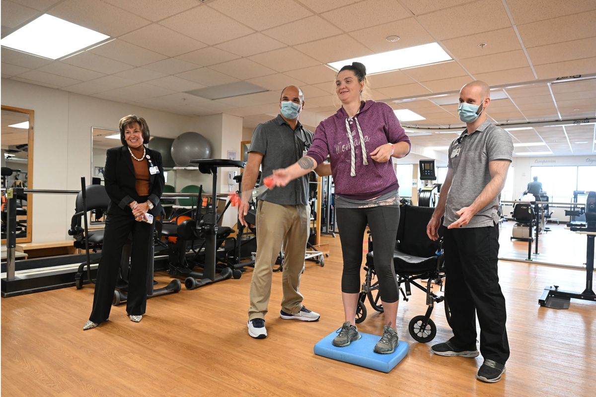 Nancy Webster, left, watches patient Karla Sliger is challenged to stand on a foam pad and toss balls at a target during therapy at St. Luke