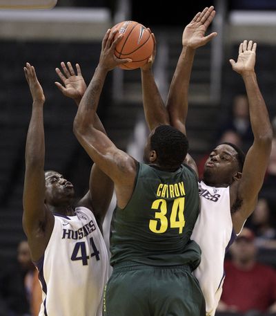 Joevan Catron is defended by UW’s Darnell Gant, left, and Matthew Bryan-Amaning. (Associated Press)