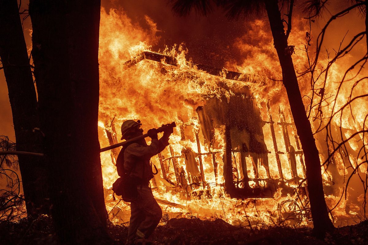 In this Nov. 9, 2018 file photo, firefighter Jose Corona sprays water as flames from the Camp Fire consume a home in Magalia, Calif. A massive new federal report warns that extreme weather disasters, like California’s wildfires and 2018’s hurricanes, are worsening in the United States. The White House report quietly issued Friday, Nov. 23 also frequently contradicts President Donald Trump. (Noah Berger / AP)