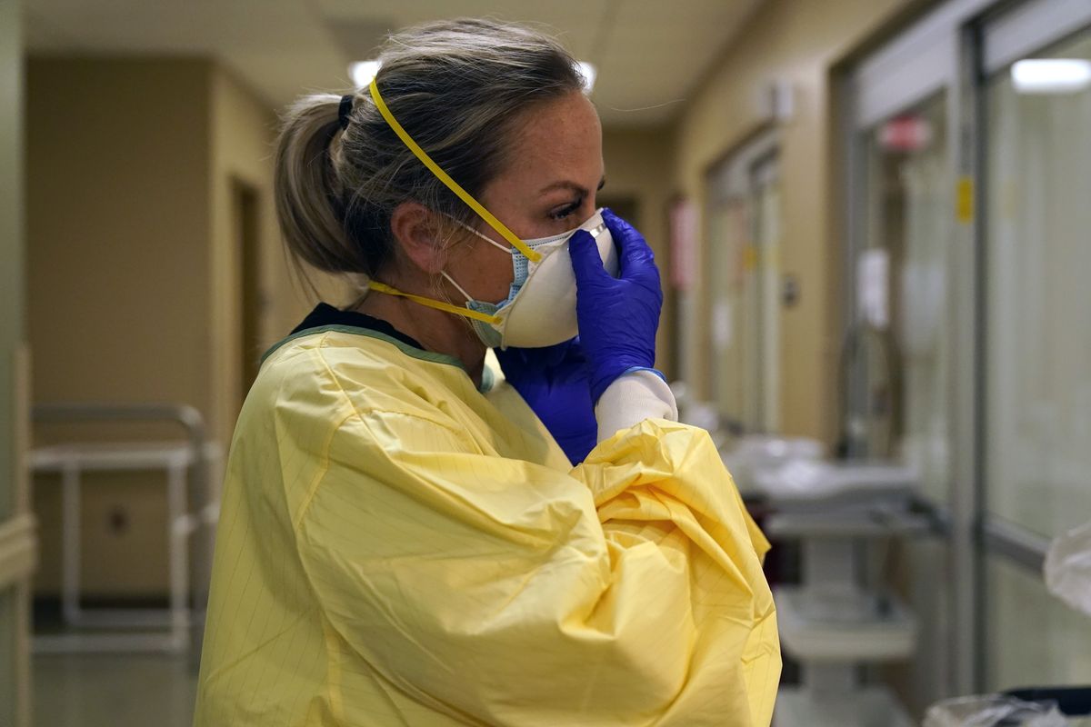 FILE - In this Nov. 24, 2020, file photo, registered nurse Chrissie Burkhiser puts on personal protective equipment as she prepares to treat a COVID-19 patient in the in the emergency room at Scotland County Hospital in Memphis, Mo. The U.S. has seen a dramatic turnaround since December and January, when hospitals were teeming with patients after holiday gatherings and pandemic fatigue caused a surge in cases and deaths.  (Jeff Roberson)