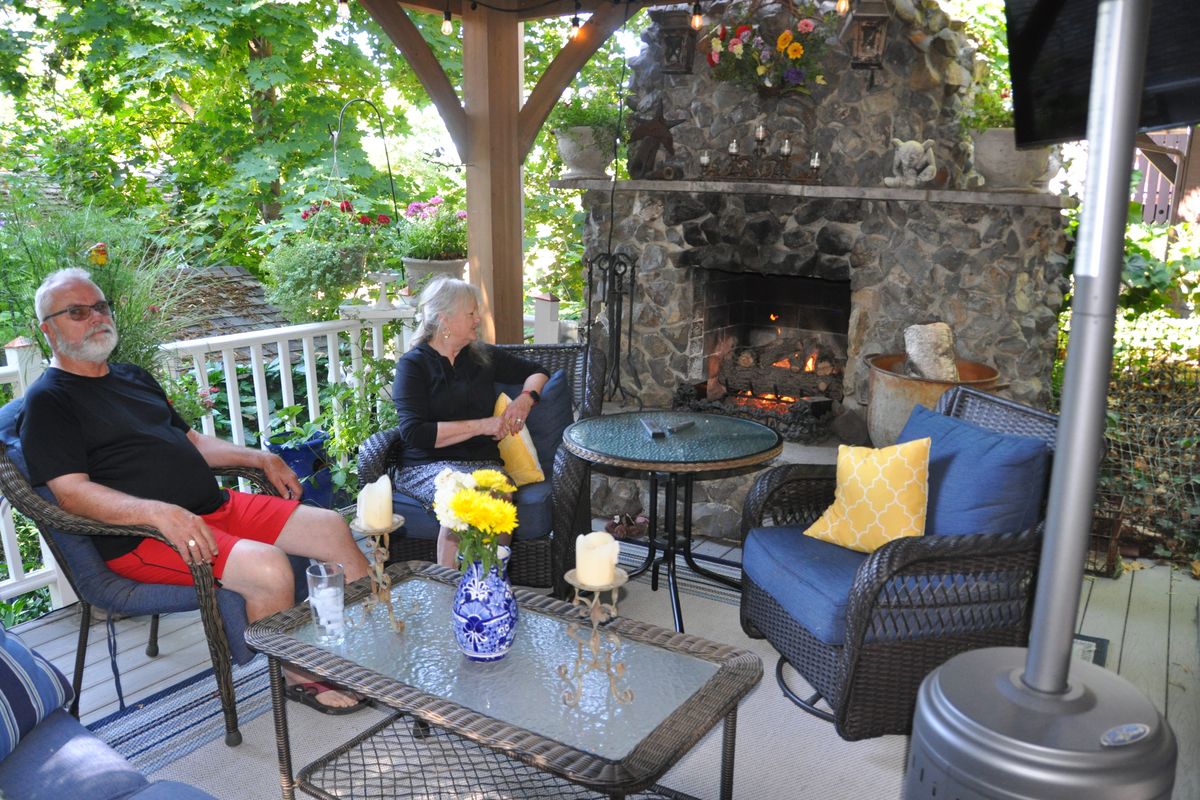 Ed and Rita Everstine relax in their outdoor room next to the basalt rock fireplace Ed built. The space is cozy enough to enjoy during winter.  (Pat Munts/For The Spokesman-Review)
