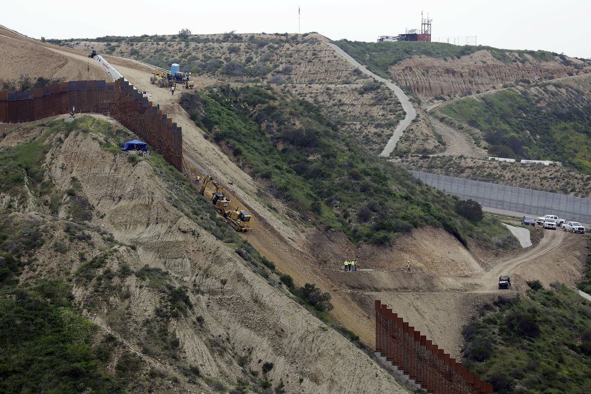 FILE - In this March 11, 2019, file photo, construction crews replace a section of the primary wall separating San Diego, above right, and Tijuana, Mexico, below left, seen from Tijuana, Mexico. The Biden administration says it will begin work to address flooding and soil erosion risks from the unfinished wall on the U.S. border with Mexico. It also began providing answers on how it will use unspent money from shutting down one of President Donald Trump