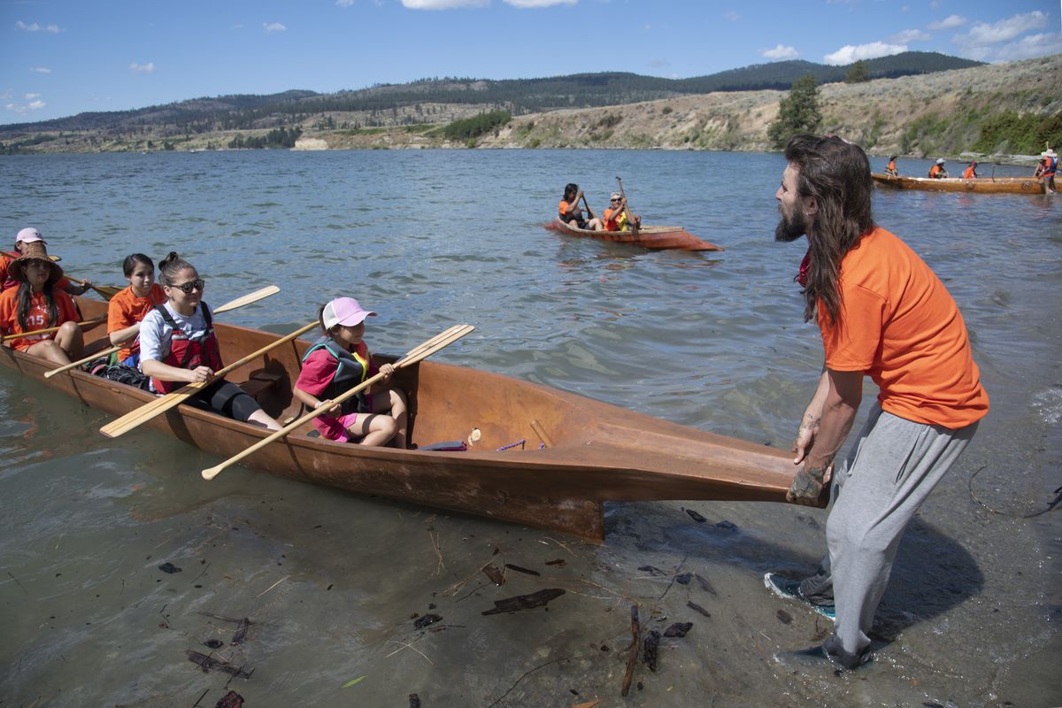 Devon Peone helps launch one of two traditional cedar canoes Tuesday as they prepare to leave the confluence of the Spokane and Columbia  (Jesse Tinsley/The Spokesman-Review)