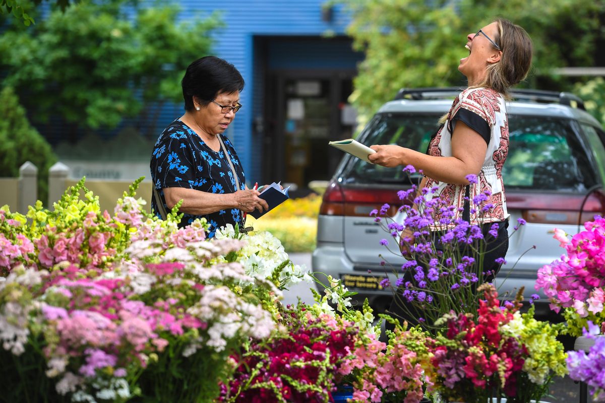 Beth Mort, of Snapdragon Flower Farm, right, breaks out in laughter while helping Gilded Lily owner Toi Mulligan, left, during the Inland Northwest Flower Farmers Market, Wednesday, July 10, 2019, at the Spokane County Conservation District. (Dan Pelle / The Spokesman-Review)