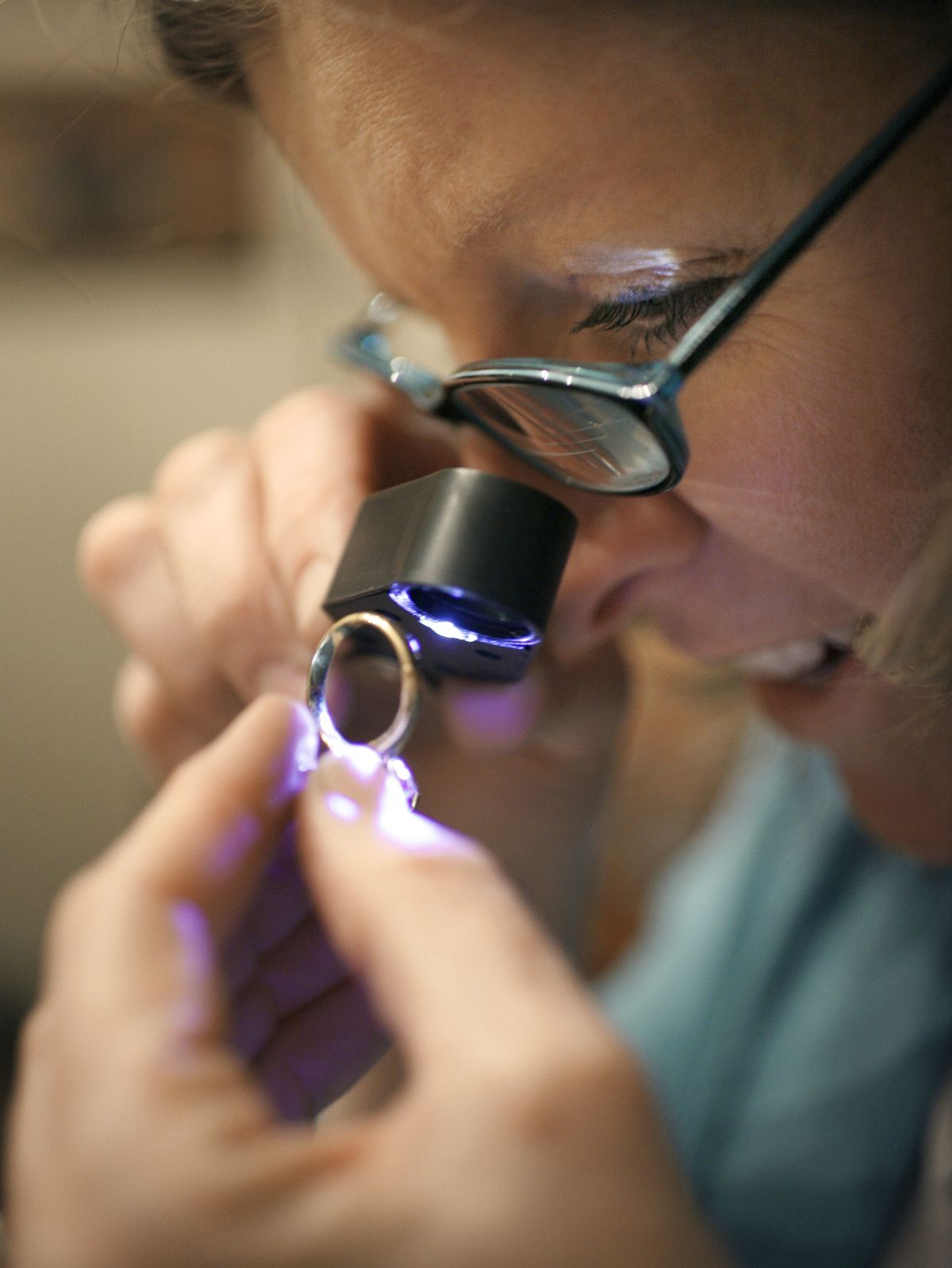 Gold tester Maggie Percival, of Granby, Conn., looks at a gold ring through a jewelers loupe during a gold party at a private home. Like the Tupperware parties from years ago, gold parties tap into a host’s social connections to drive up attendance, while the presence of friends helps reassure partygoers that selling gold isn’t taboo. (Associated Press / The Spokesman-Review)