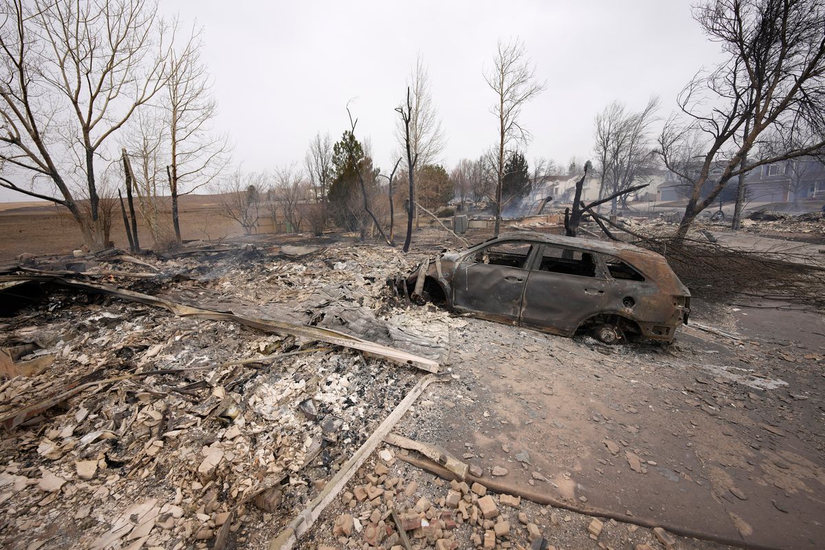 Debris surround the remains of homes burned by wildfires after they ripped through a development, Friday, Dec. 31, 2021, in Superior, Colo. Tens of thousands of Coloradans were driven from their neighborhoods by wind-whipped wildfires.  (David Zalubowski)