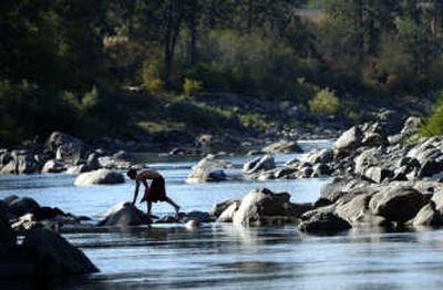 
Jared Moore, 17, walks across the Spokane River near Sullivan Road on Tuesday using exposed boulders to stay out of the water. 
 (Holly Pickett / The Spokesman-Review)