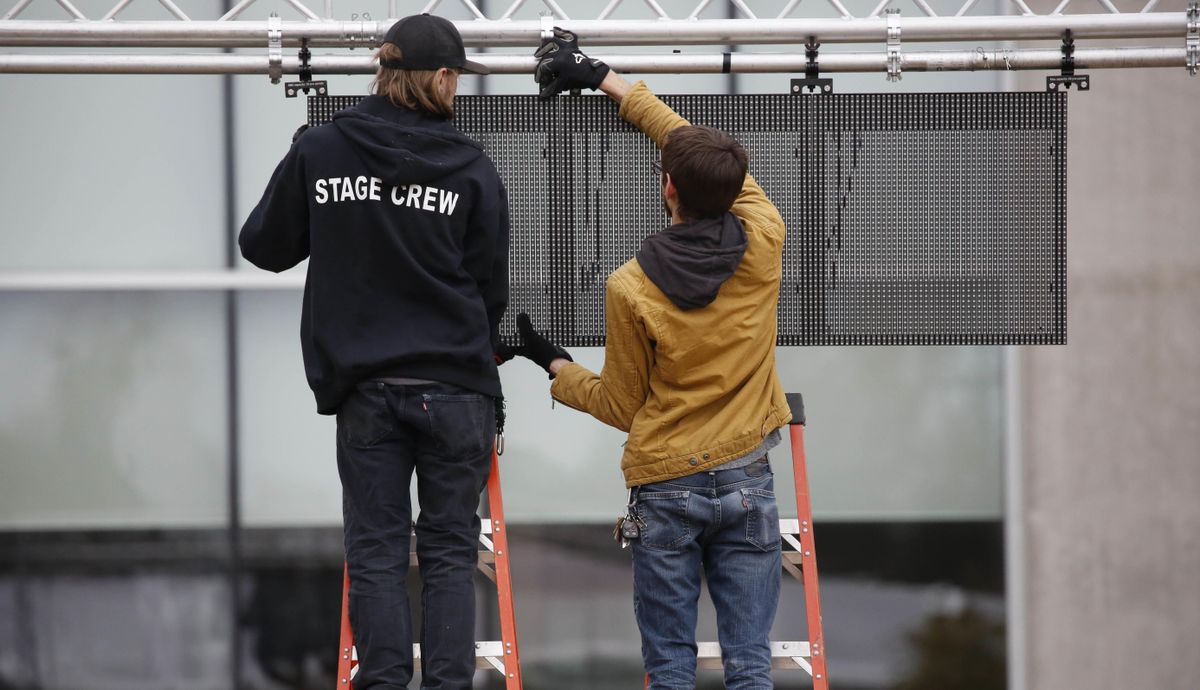 Workmen construct a lighted panel near the stage before the state