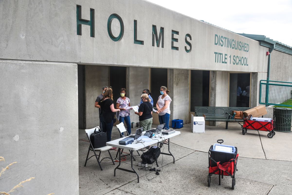 Volunteer nurses gather for instruction before the Spokane Regional Health District conducts curbside COVID-19 testing at Holmes Elementary School, July 7, 2020, in Spokane. Spokane Public Schools on Monday announced that when school resumes in the fall, it will start in distance-learning mode.  (Dan Pelle / The Spokesman-Review)