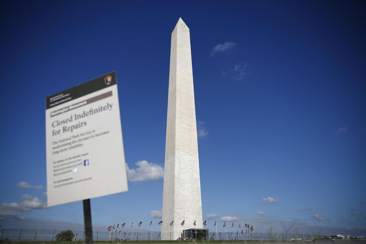 The Washington Monument is seen past a sign greeting visitors during a press preview tour ahead of the monument