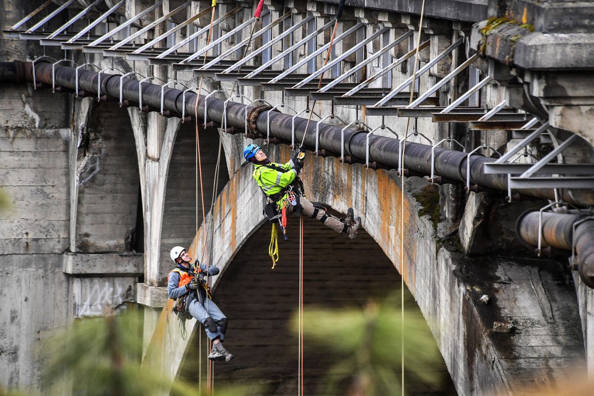 Jeremy Miles, of HDR Engineering, left, and Zach Williams, of Fickett Structural Solutions, inspect the northwest side of the 140-foot-tall Latah Creek Bridge for deterioration on March 11, 2020 in Spokane. Miles says he feels safer hanging on the rope than climbing a ladder. (Dan Pelle / The Spokesman-Review)