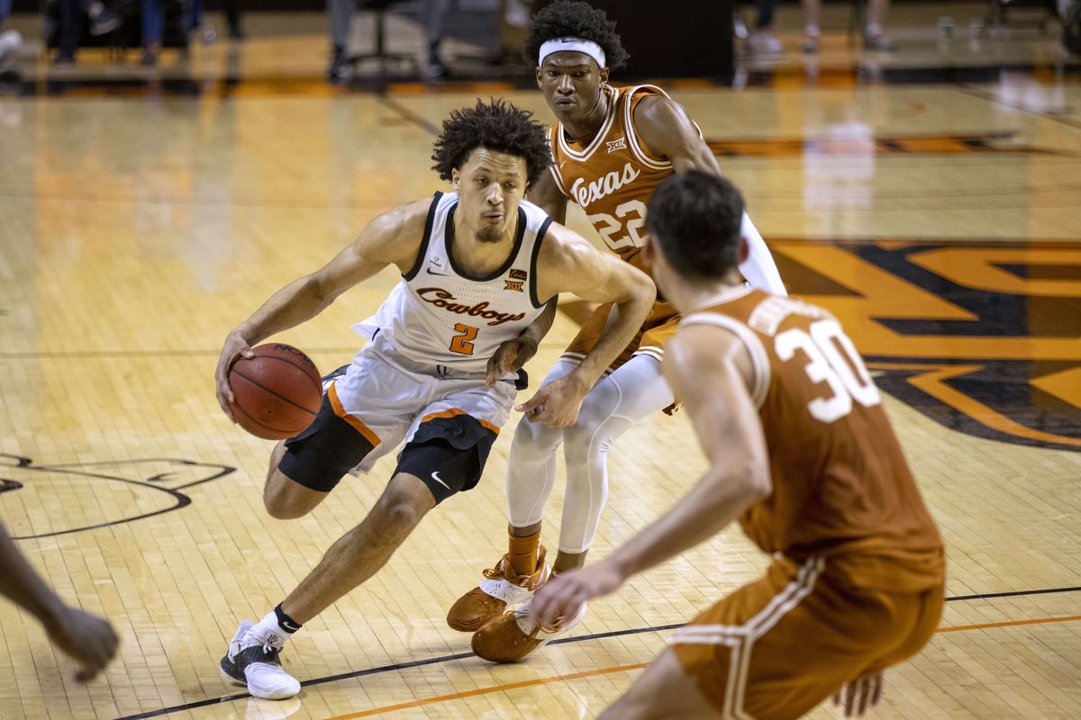 In this Feb. 2021 photo, Oklahoma State guard Cade Cunningham (2) drives past Texas forward Kai Jones (22) and Brock Cunningham (30) during the first overtime of the NCAA college basketball in Stillwater, Okla. Cunningham is a 6-foot-8 ballhandler with the ability to play on or off the ball. He