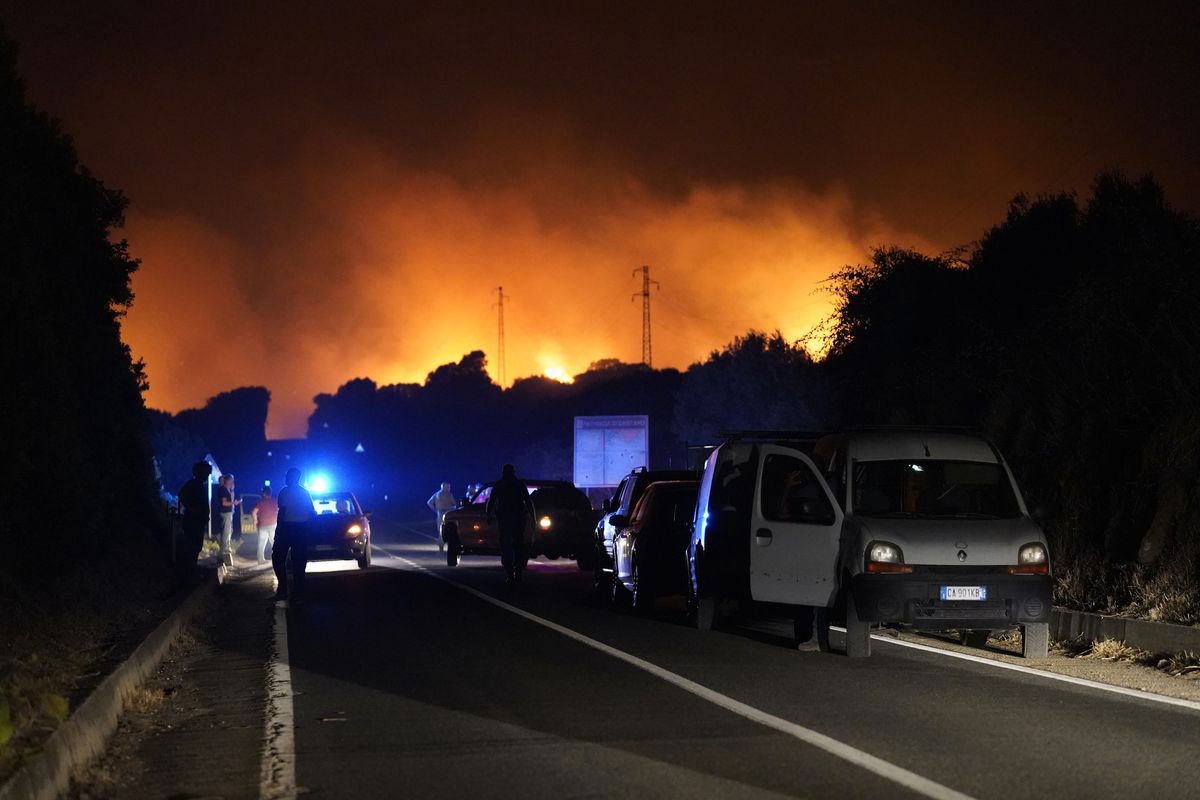 Cars are parked by the road as fires have been raging through the countryside in Cuglieri, near Oristano, Sardinia, Italy, early Sunday, July 25, 2021. Hundreds of people were evacuated from their homes in many small towns in the province of Oristano, Sardinia, after raging fires burst in the areas of Montiferru and Bonarcado.  (Alessandro Tocco)