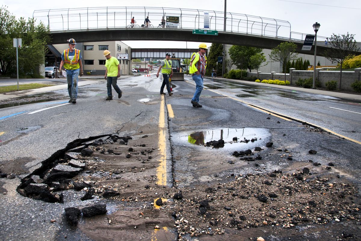Workmen inspect the damage to Hamilton Street in Spokane on Friday after a 12-inch water main broke and flooded the area. (Dan Pelle)
