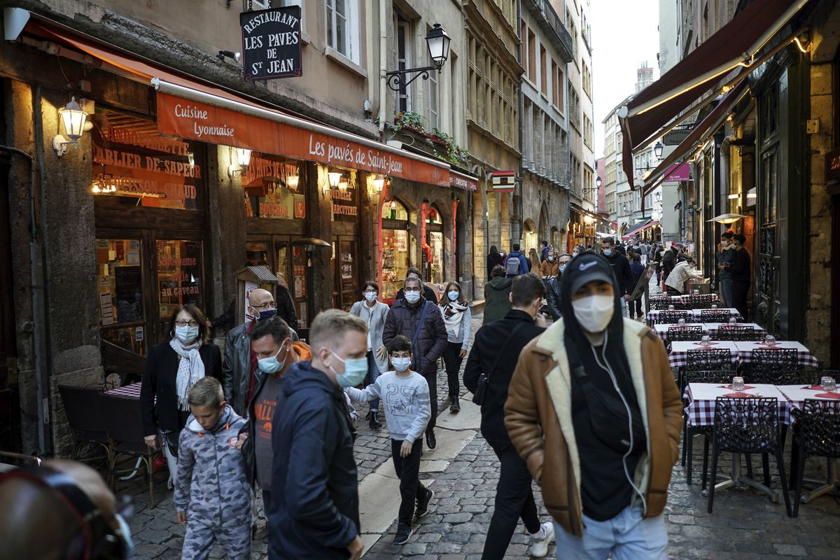People wearing masks pass by restaurants in the center of Lyon, central France, Saturday, Oct. 10, 2020. Starting Saturday, Lyon has been placed under maximum virus alert. The maximum alert level implies shutting down bars, implementing stricter measures in restaurants and limiting private gatherings. (Laurent Cipriani)