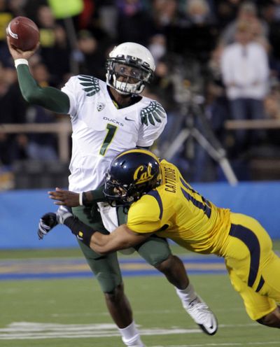 Oregon QB Darron Thomas gets a pass off under pressure from Cal’s Sean Cattouse on Saturday. (Associated Press)